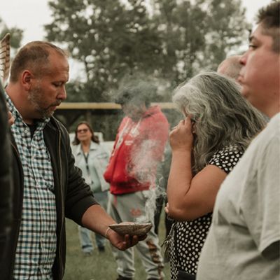 Photo of people who identify as Indigenous performing a ceremony involving smoke.