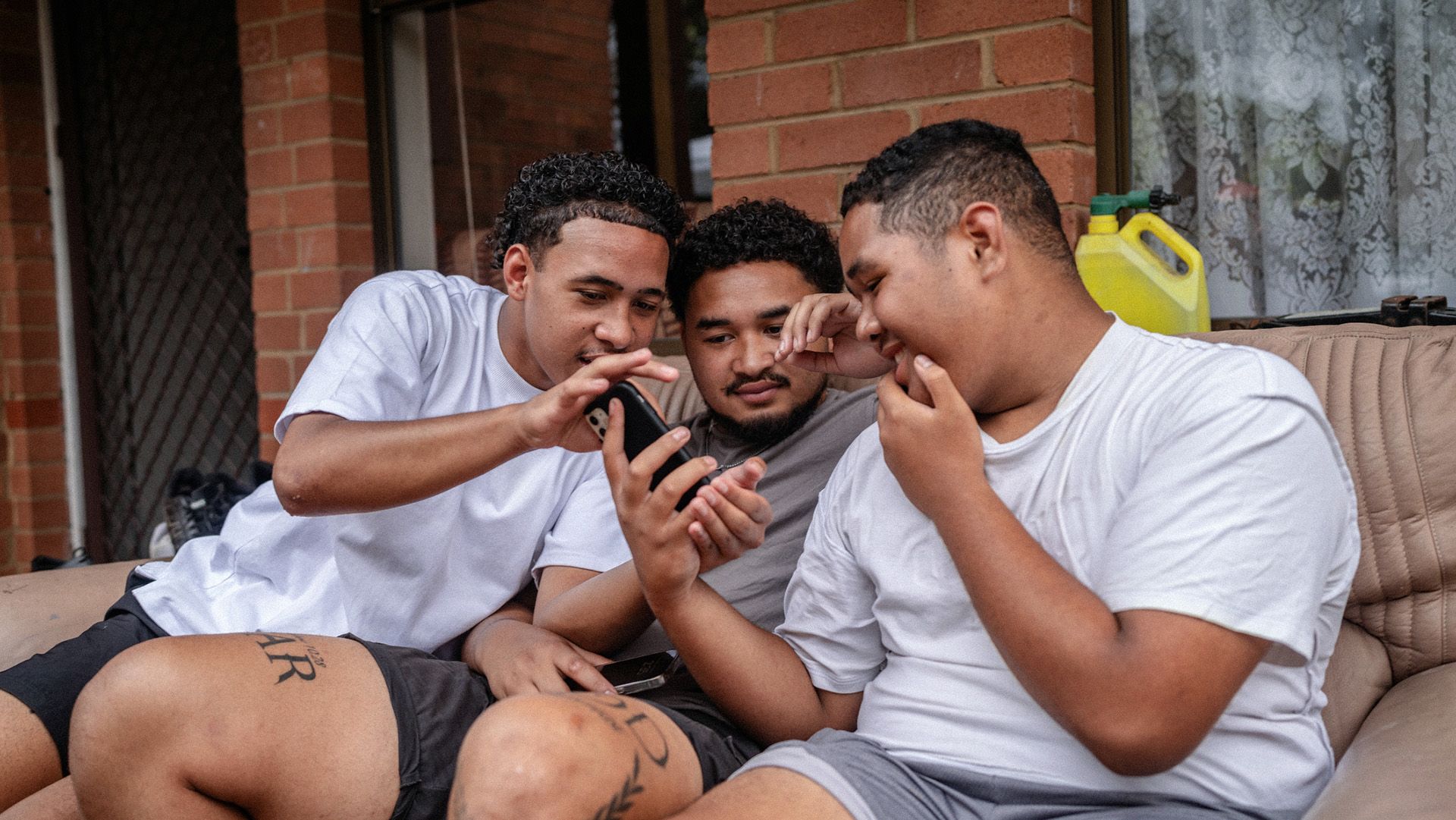 Photo of three young men, thoroughly getting into something on a smartphone.