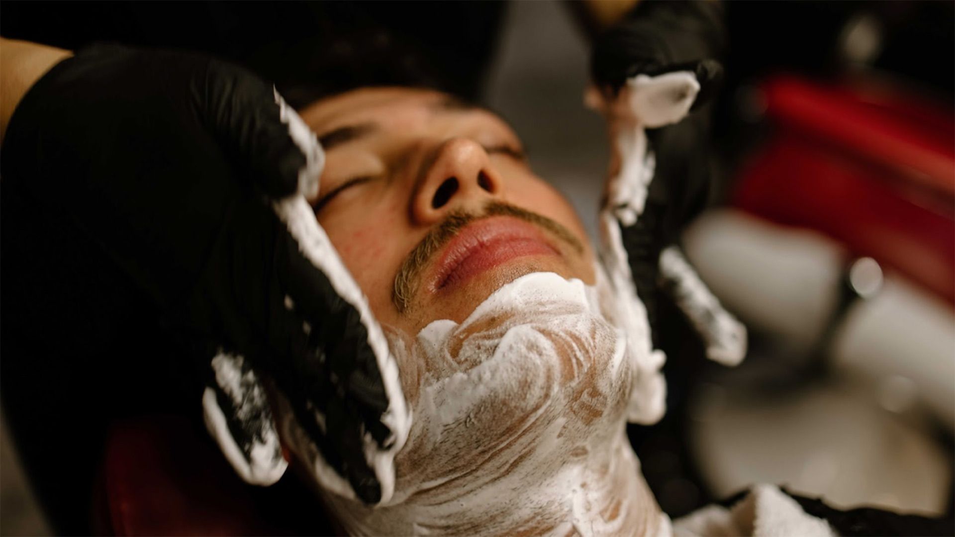 Photo of a man lying down while receiving a hot shave.